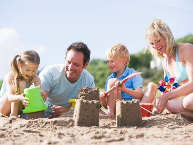 Children making sand castles with parents